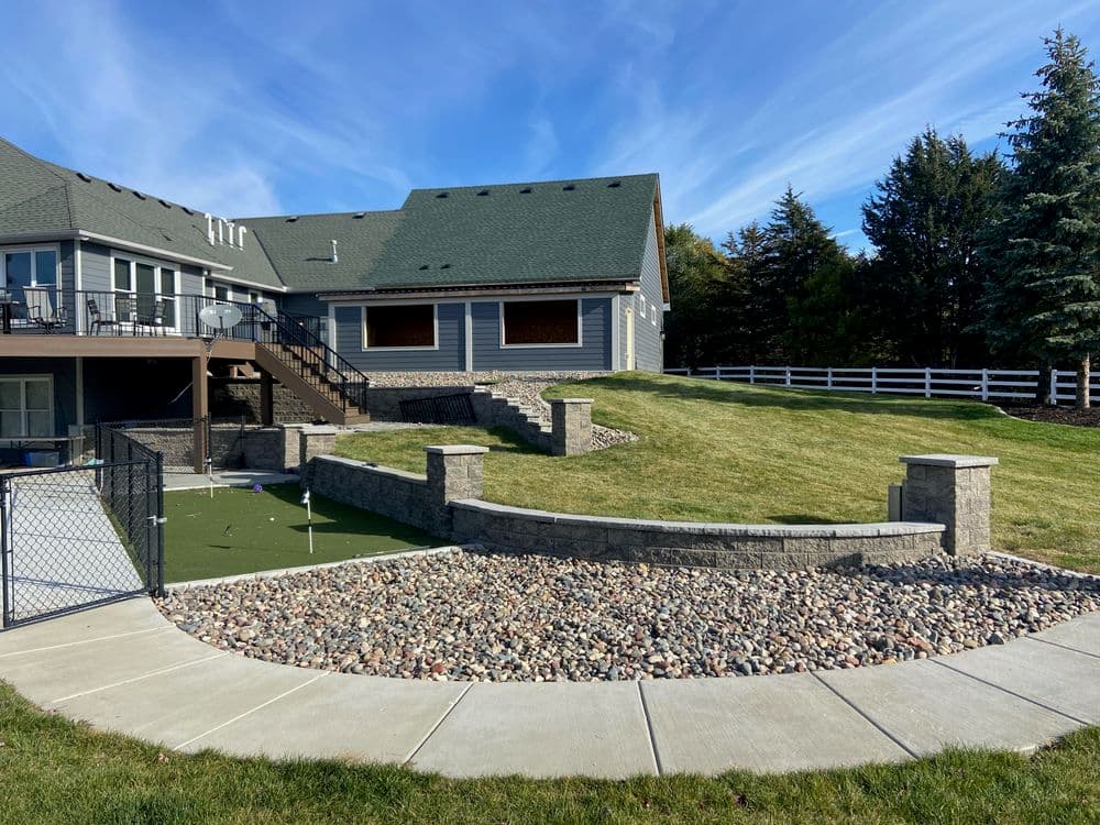 Landscape design featuring a stone wall and artificial turf in a residential backyard setting.